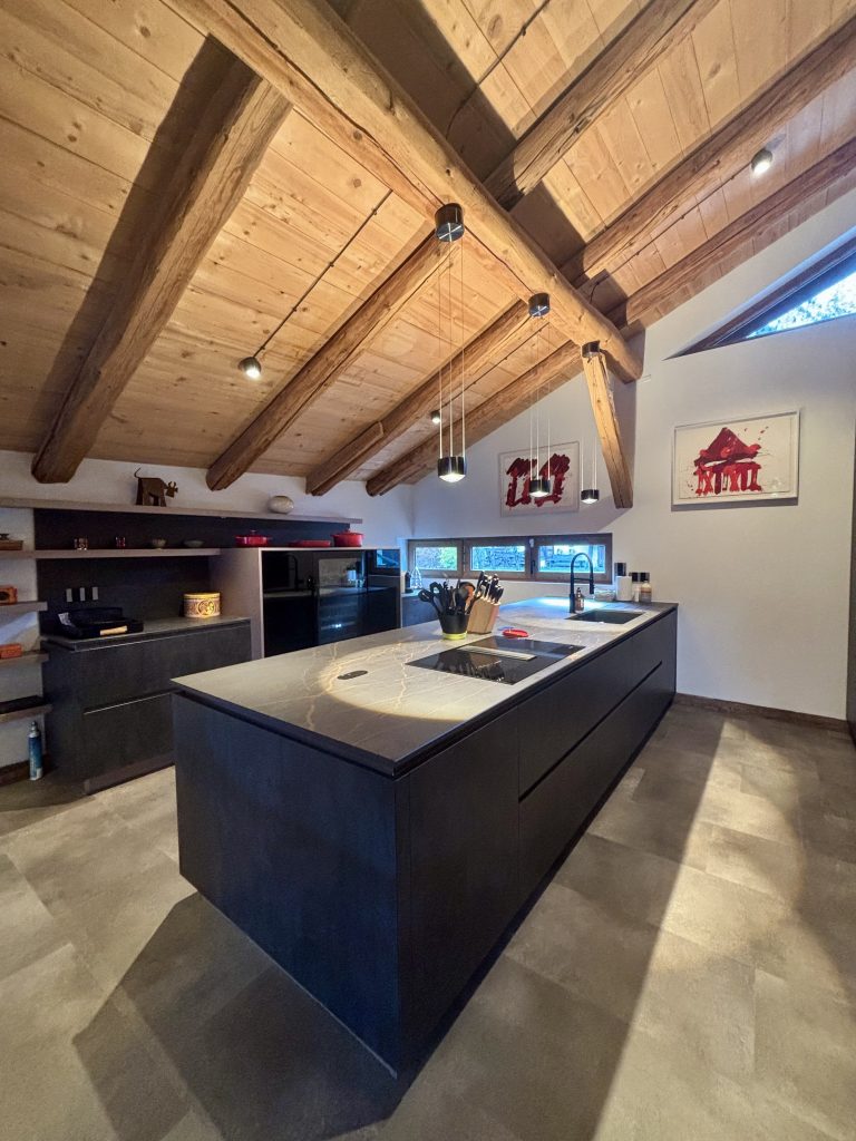 Cuisine rénovée dans un chalet, avec mobilier moderne, plan de travail fonctionnel et décoration contemporaine.