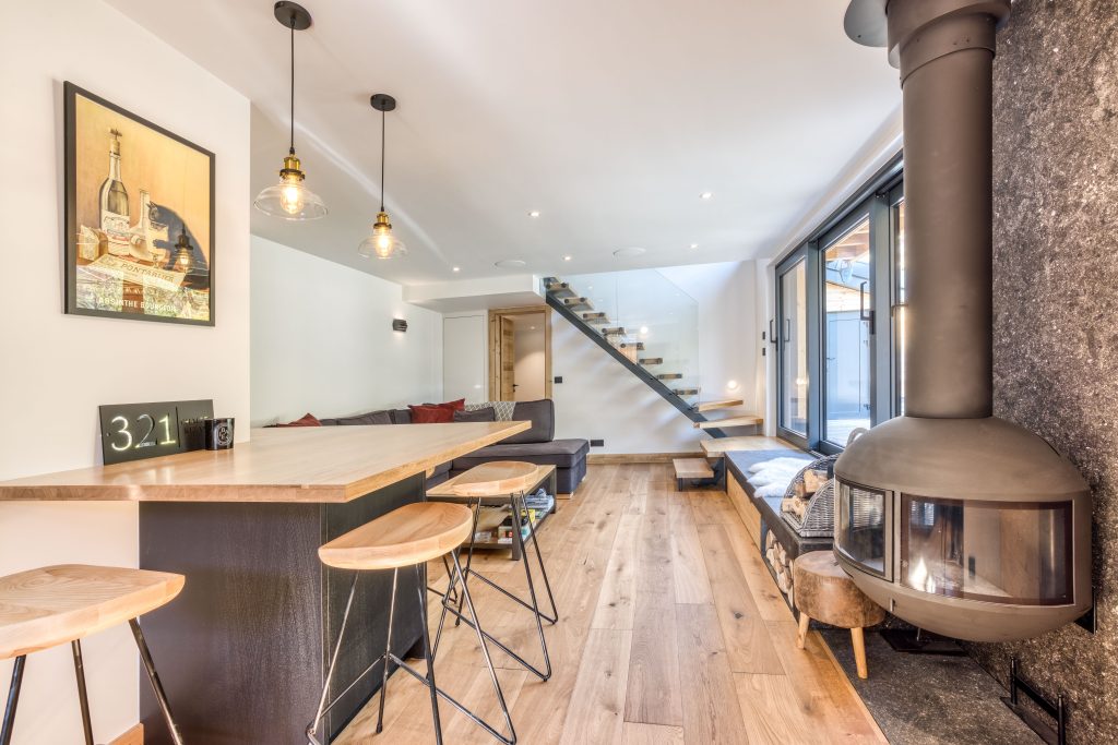 Salon rénové dans un chalet avec cheminée, mobilier confortable et ambiance chaleureuse et cosy.